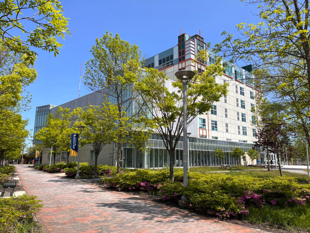 Exterior photograph of the Osher Map Library building in the spring. Trees have green leaves and the sky is clear.